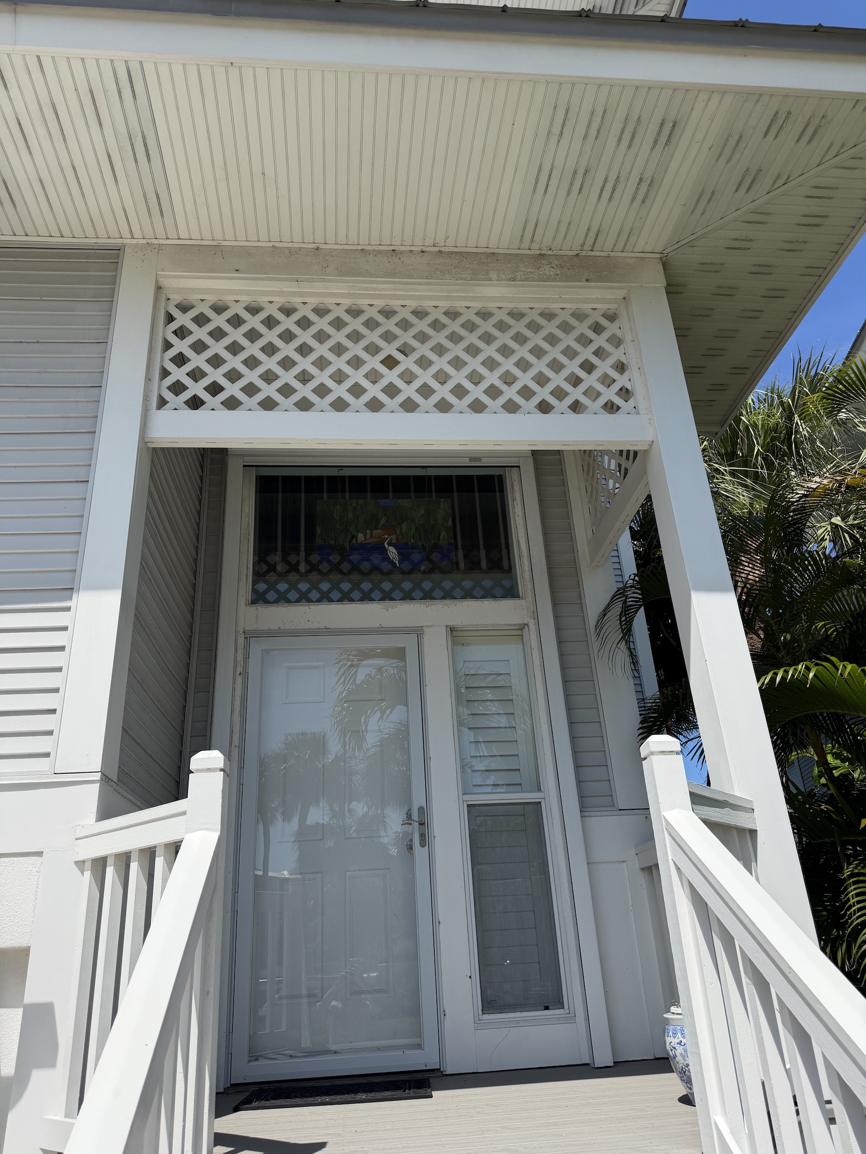 Front entry before and after — porch, lattice, transom trim, and railings refreshed.