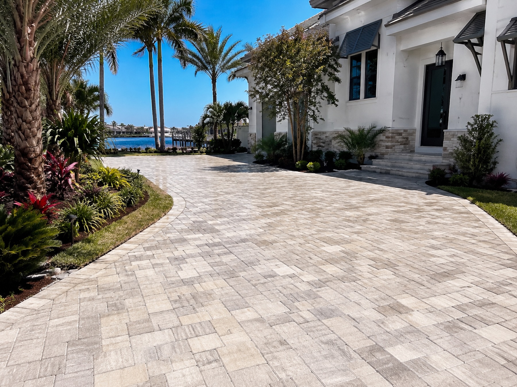 Illustrative driveway and apron — patterned pavers leading to a coastal garage.