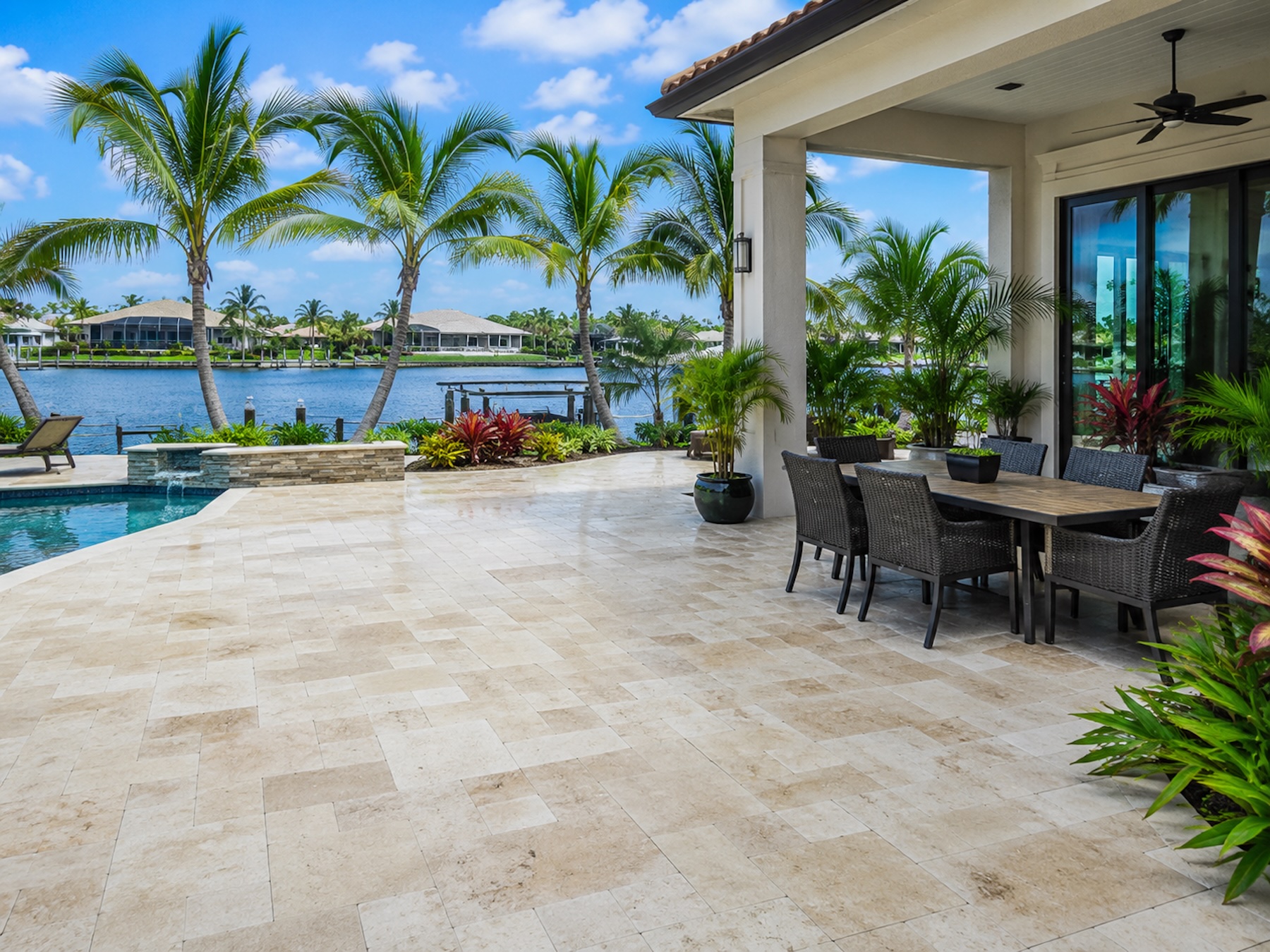 Illustrative pool-deck patio — light stone pavers around a residential pool.