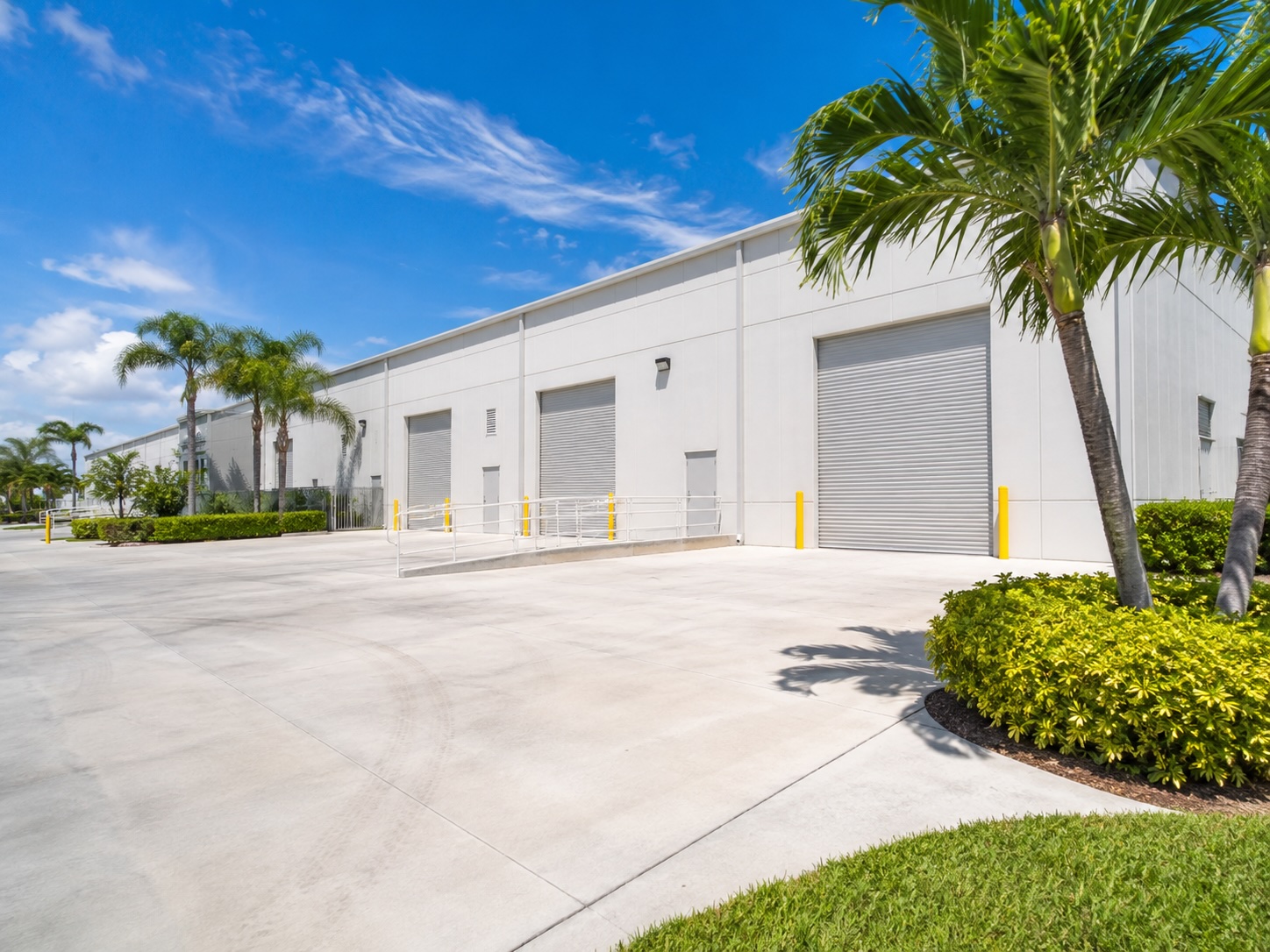 Illustrative warehouse exterior rinse — loading apron and metal cladding.