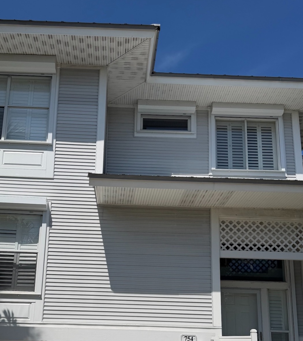 House wash before and after — two-story home with gray siding and white trim.